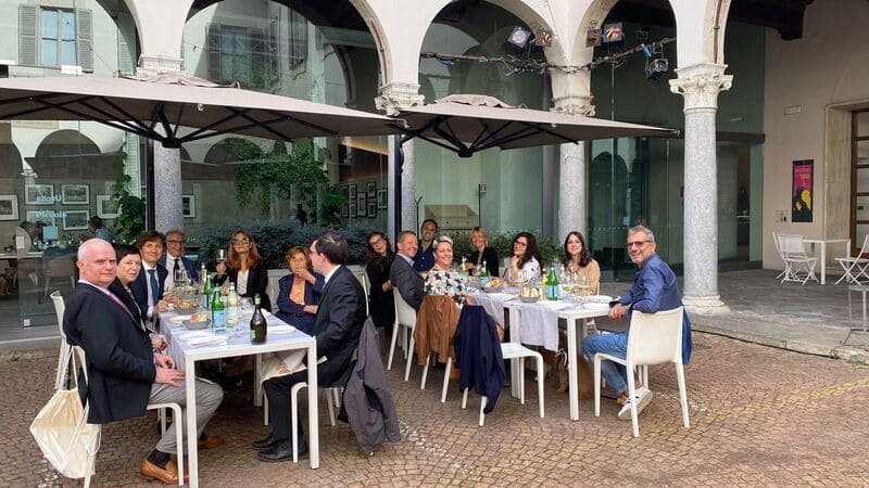 Un gruppo di persone sedute a due tavoli condividono un momento di convivialità