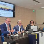 L'immagine di un convegno con tre relatori seduti a un tavolo